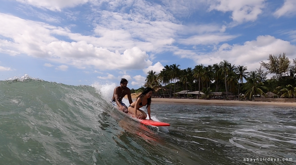 Instructor supporting a learner on a surfboard